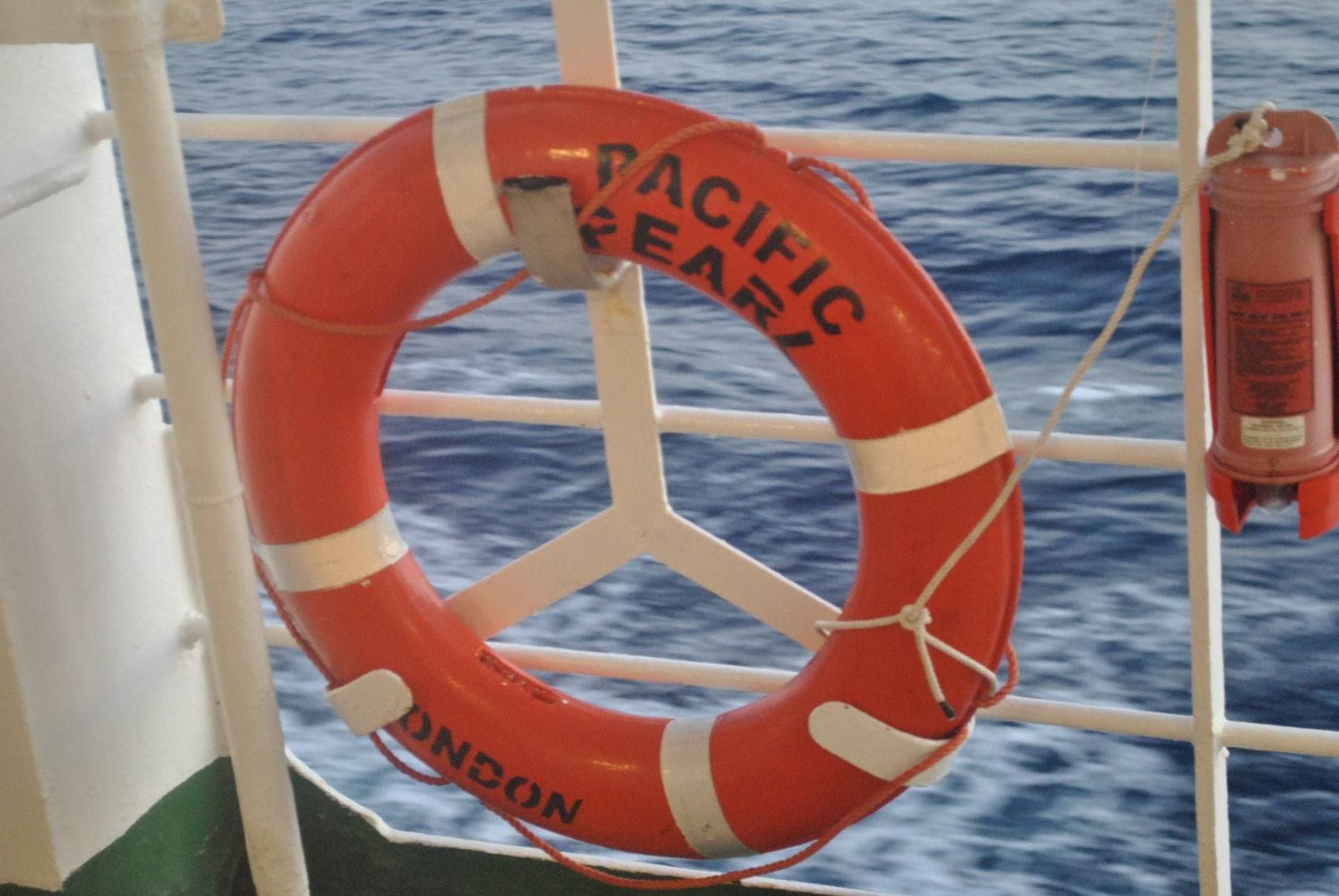 Bóia salva-vidas presa à amurada de um navio, sobre o mar